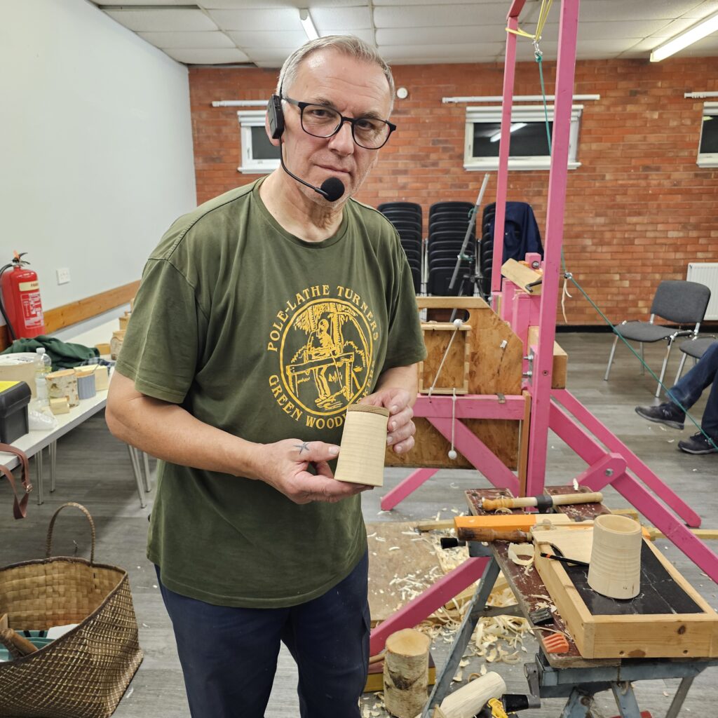 Picture of Dave Stovell holding a Shrink Pot, garish pink lathe in the background
Credit C Griggs